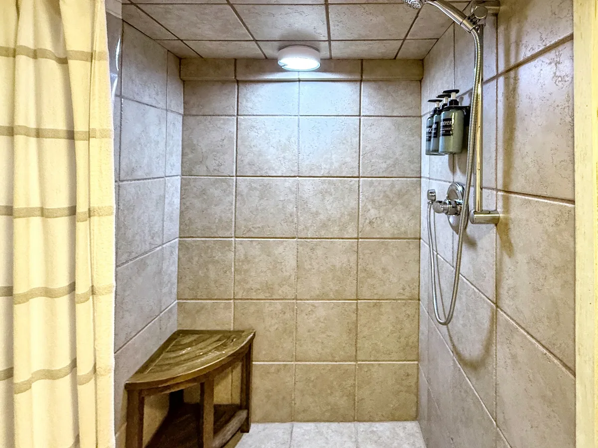 A spa-like shower with a sleek showerhead, calming wooden bench, and subtle natural or soft lighting. The space exudes a tranquil atmosphere, designed for relaxation after a long day or a refreshing start to the morning.